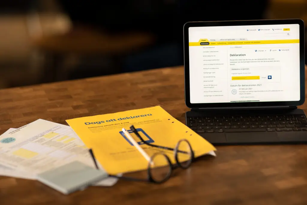 Deklarationsdokument från Skatteverket tillsammans med en surfplatta som visar Skatteverkets deklarationssida.