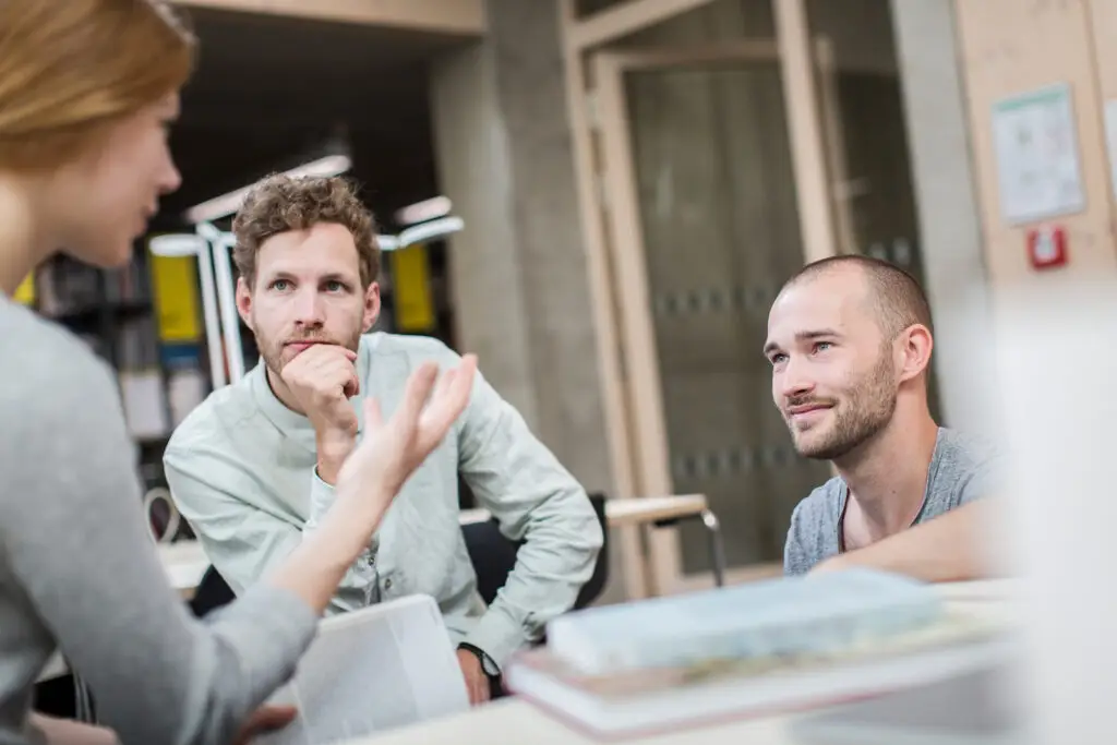 Tre personer i diskussion på kontor, som illustrerar rådgivning och samarbete för företagsutveckling.